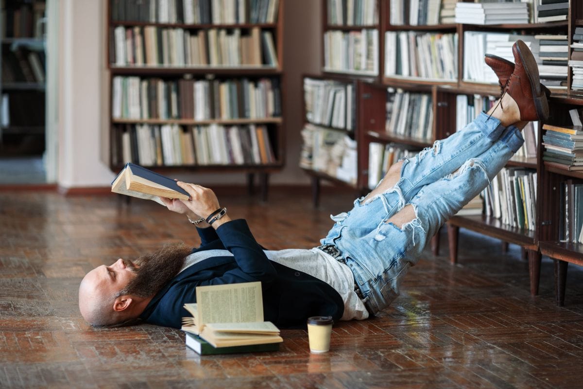 man lying on the floor reading a book representing what is a dilettante